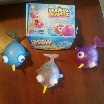 three narwhal figures in blue white and purple 