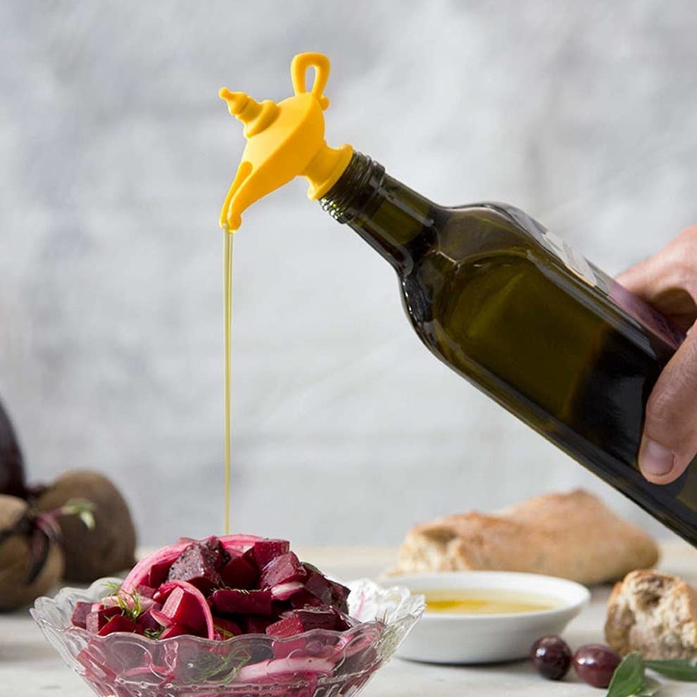 a hand using the stopper to slowly our oil over a beet salad 