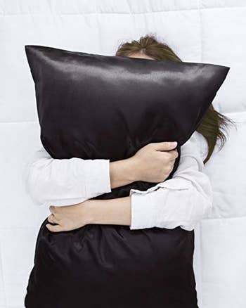 Model hugging a black satin pillow