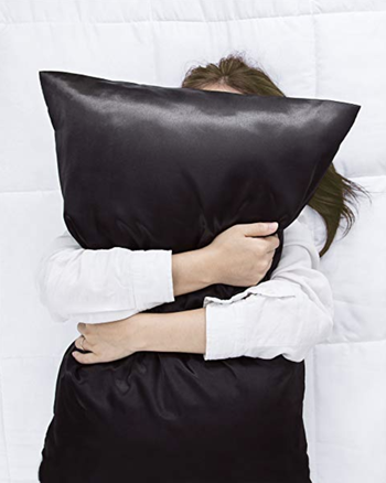 A model hugging a pillow with a black satin case