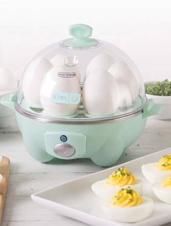 The egg machine with a transparent dome lid showing six eggs cooking in it