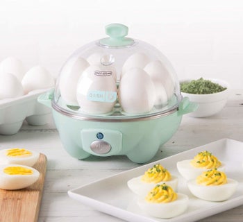 The egg machine with a transparent dome lid showing six eggs cooking in it