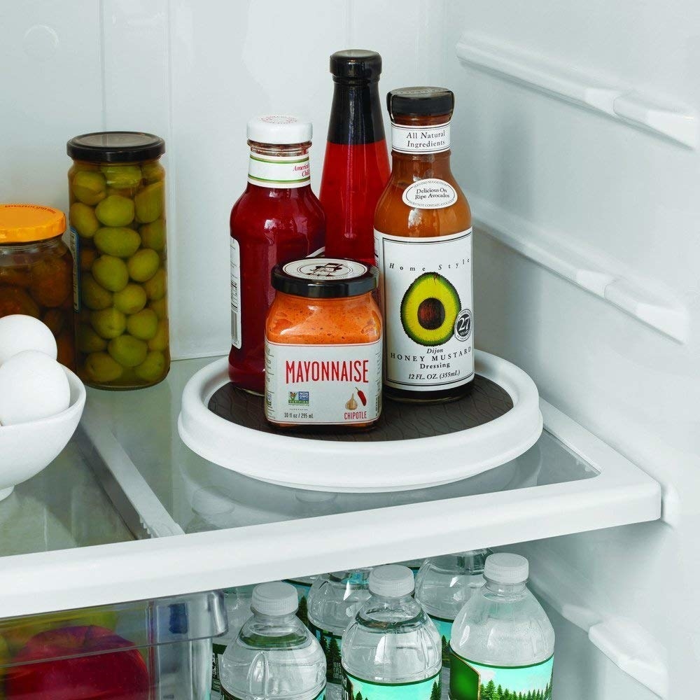 A small round lazy susan in a fridge with condiments on it  