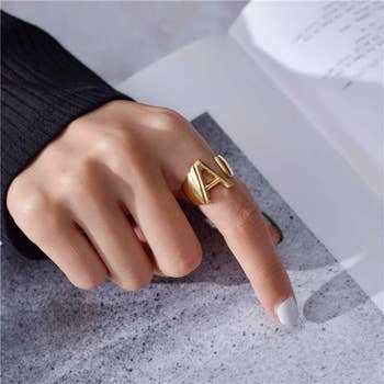 model's hand wearing the gold A initial ring 
