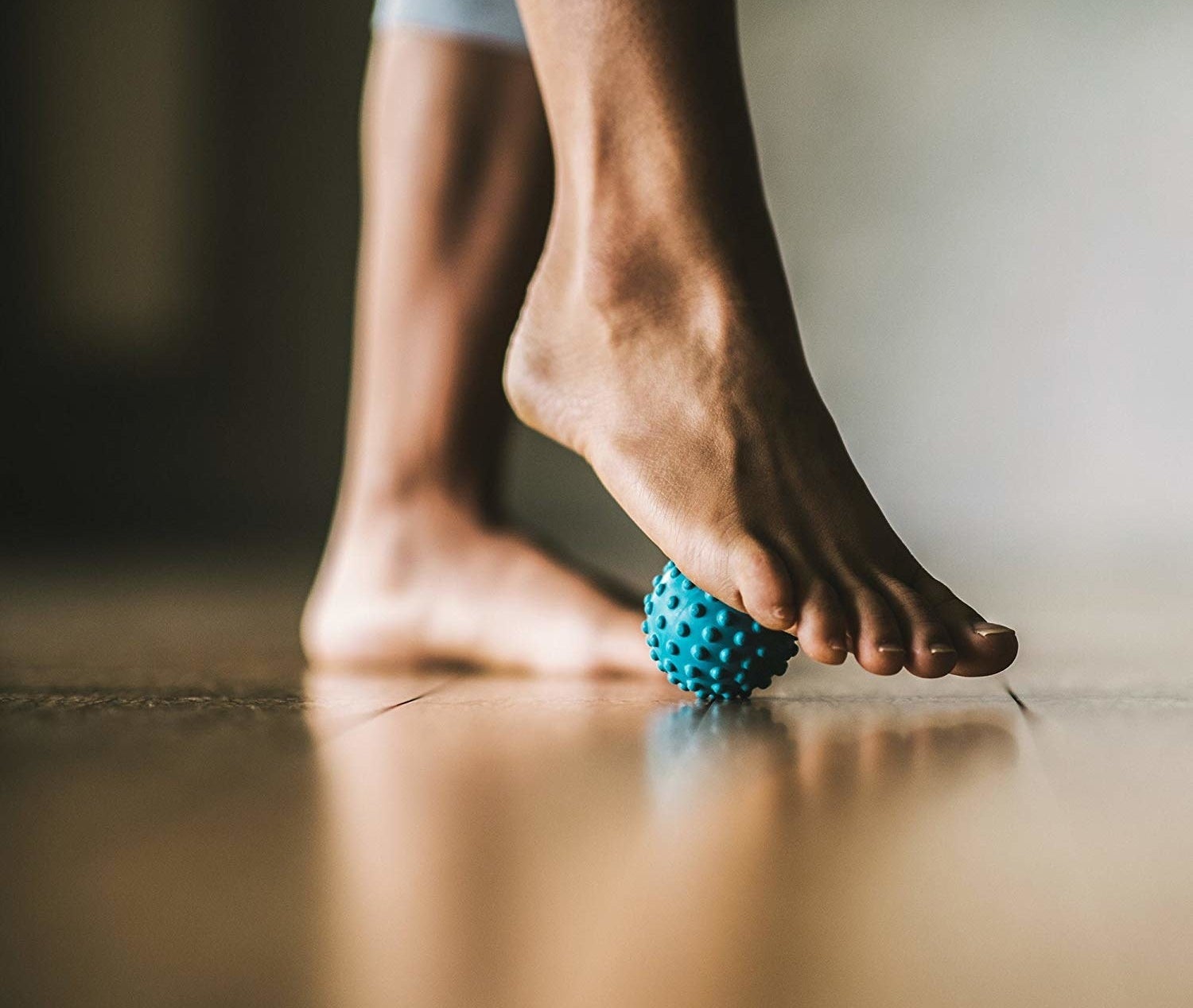 A person rolling their foot over a tiny spiky rubber ball