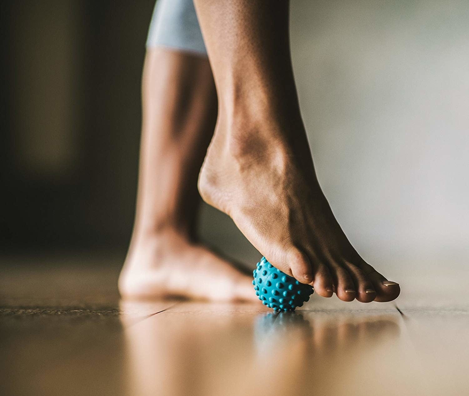 A person rolling their foot over a tiny spiky rubber ball