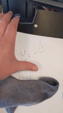 a moving gif of a hand erasing some writing from the reusable notebook