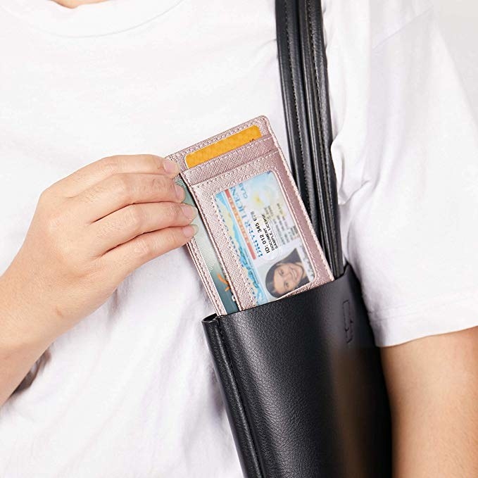 Hand pulls pink RFID-blocking credit card holder out of black tote bag