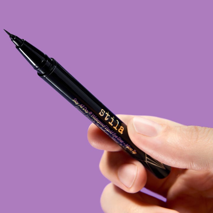 A hand holding the black eyeliner pen