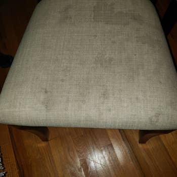 before image of white upholstered chair with stains 