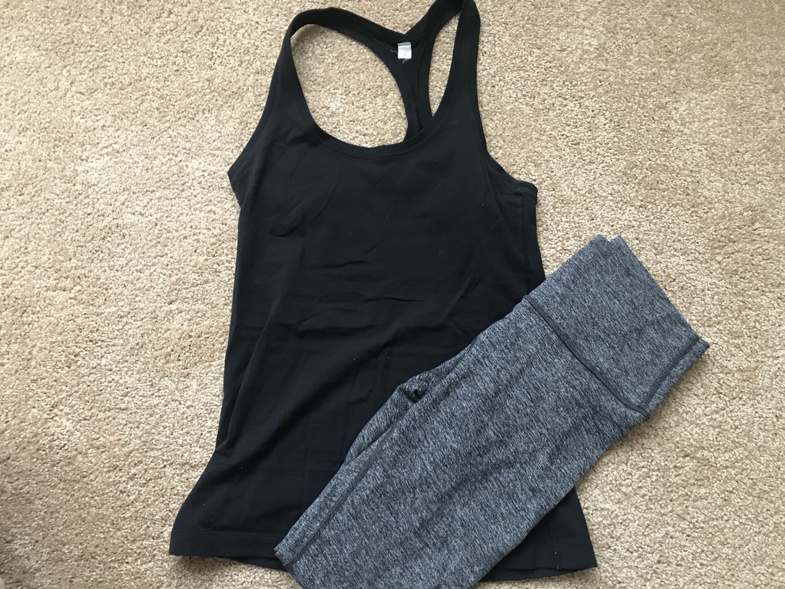 A workout top and leggings laid out on the floor