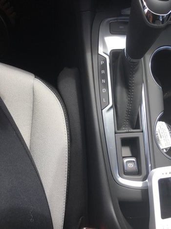 A small black seat filler wedged between the chair and console of a car