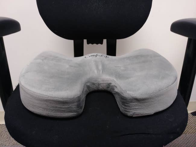 Reviewer's swivel office chair with a memory foam cushion resting on it 