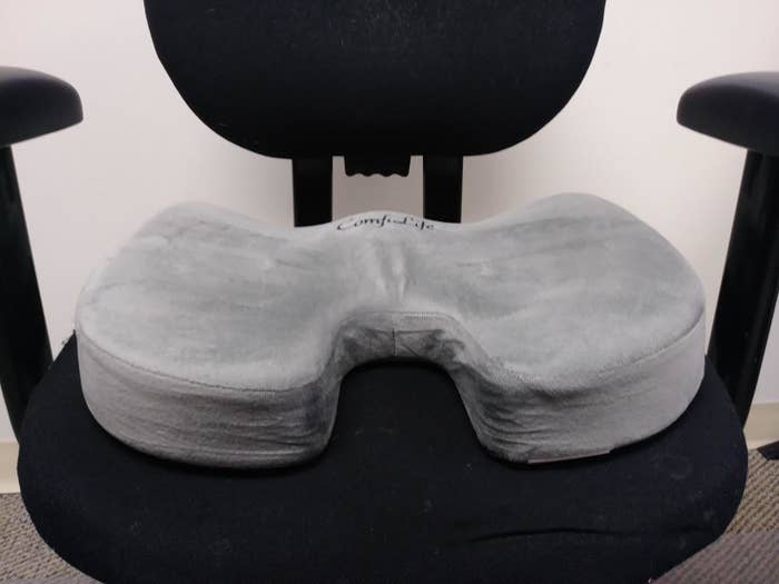A reviewer&#x27;s swivel office chair with a memory foam cushion resting on it 