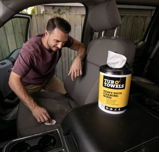 Model wipes stain off of car seat using heavy duty cleaning wipes