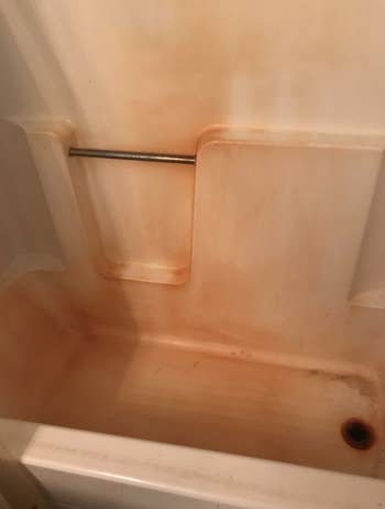 Reviewer's rusty shower tub before using a rust stain remover