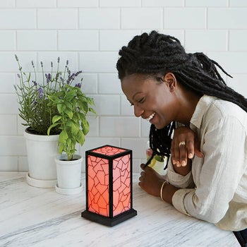 model looking at their box-shaped lamp 