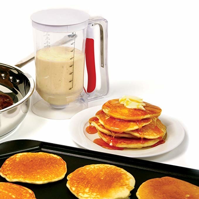 Pancake dispenser with batter in it next to a plate of pancakes.