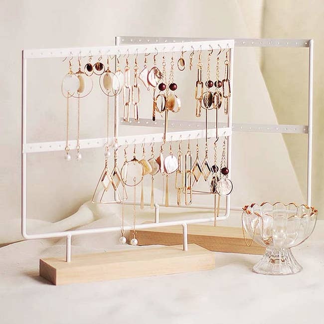 A small white two-tiered stand with tiny holes to hang earrings from 