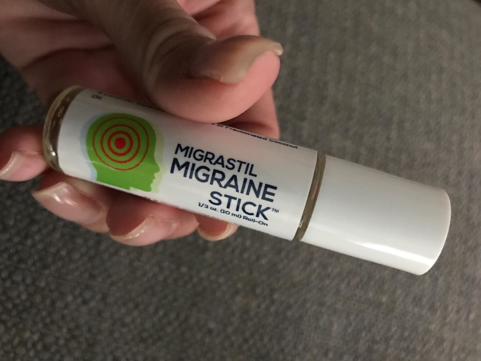 Reviewer holding tube of roll on migraine stick 