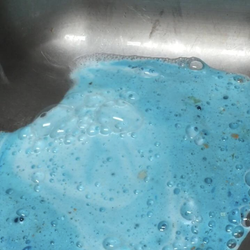 Reviewer's kitchen disposer erupting like a blue volcano from the sink 