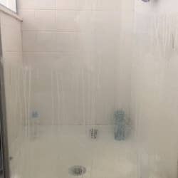 Reviewer's grimy shower door before using the power scrubber cleaning kit