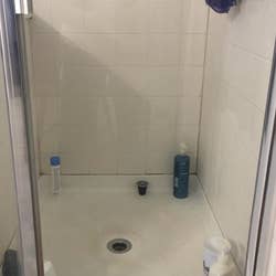 Reviewer's grimy shower door before using the power scrubber cleaning kit