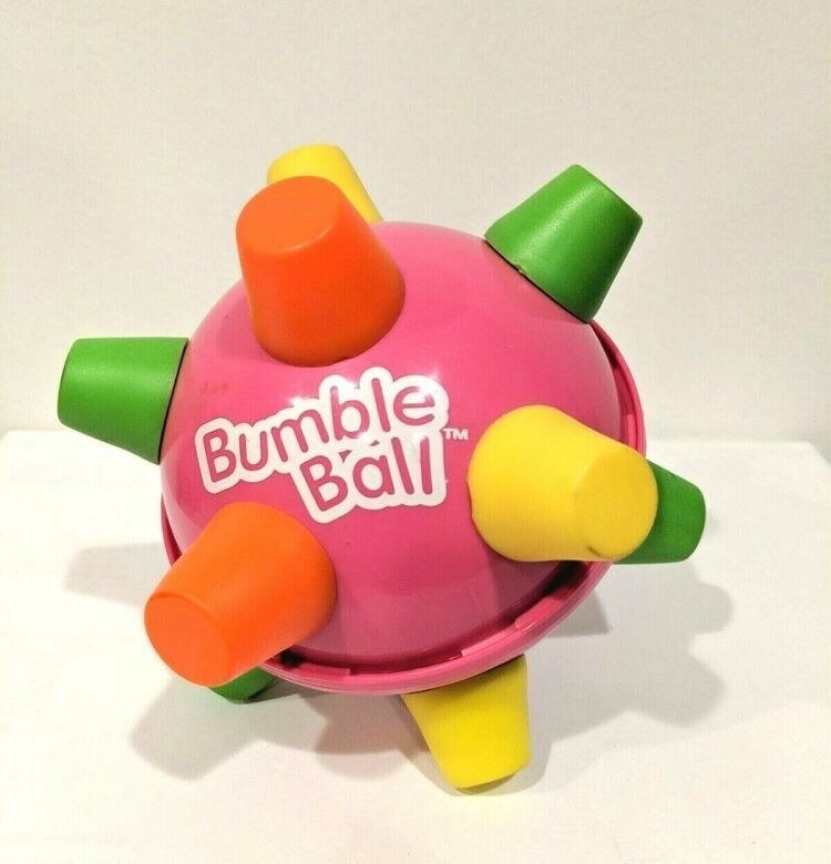 A close-up of a pink Bumble Ball with green, yellow, and orange spikes.