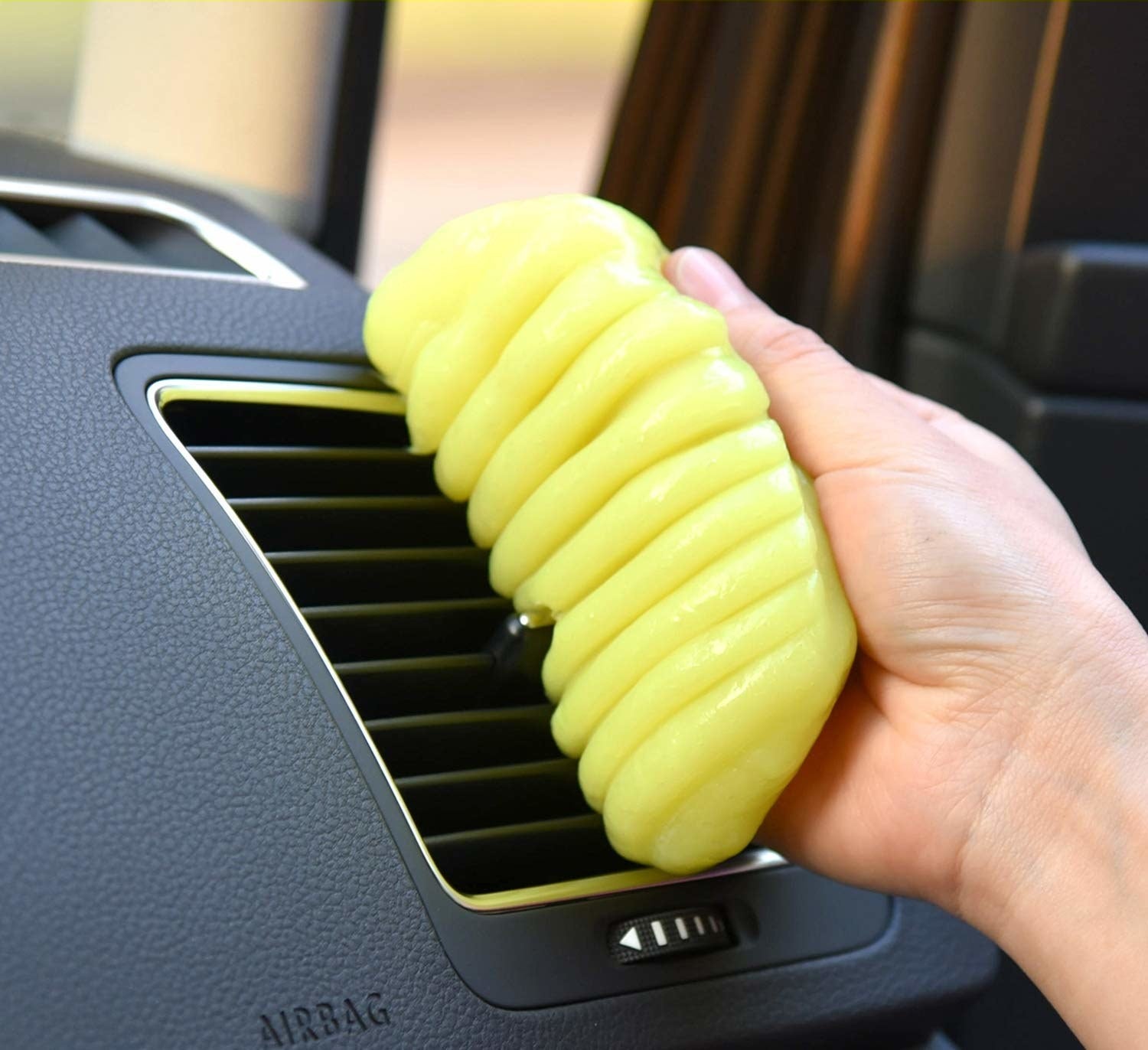 A person peeling a ball of slime off a car air vent