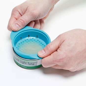 hands using tool flipped the other way to strain water from tuna can