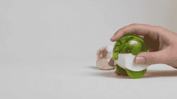 a gif of a person crushing the garlic by rolling the chopper back and forth