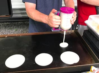 a reviewer using the dispenser to put batter on a griddle