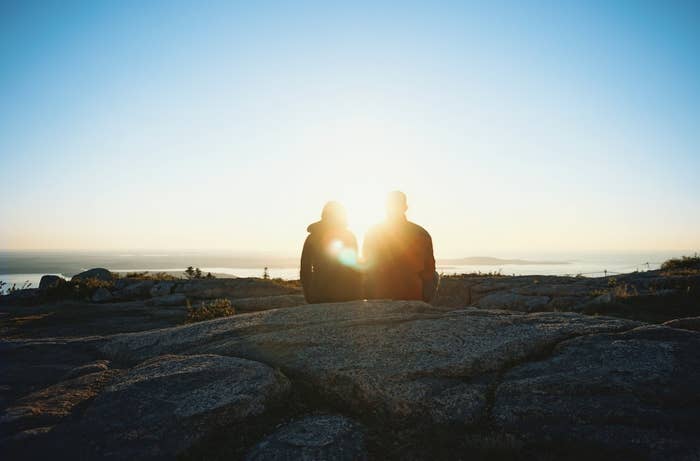 Two people sitting on a rocky ledge.