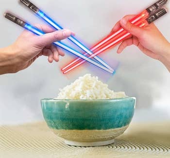 lightsaber chopsticks being held over a bowl of rice