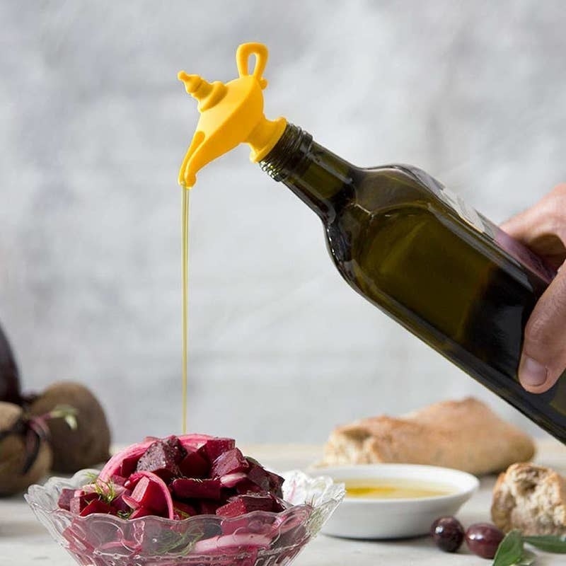 person pouring olive oil out of bottle that has the magic lamp attachment on it