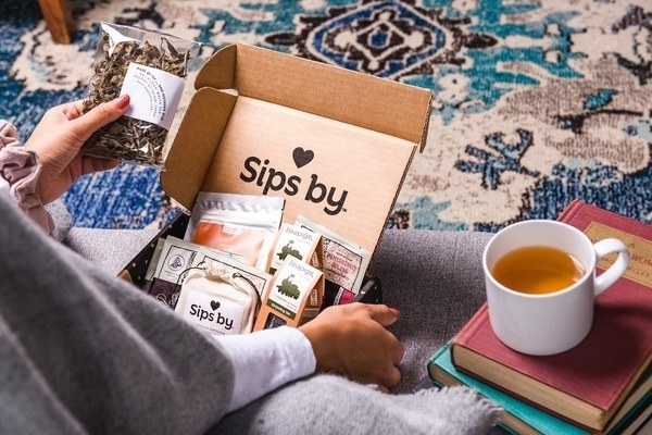 model opens box filled with various teas 