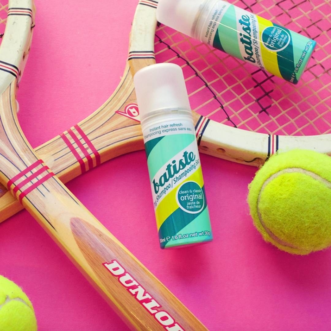 Two bottles of Batiste dry shampoo on top of tennis rackets
