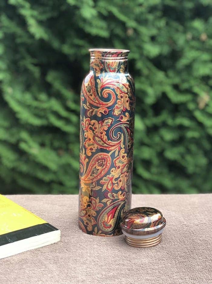 A copper water bottle with patterns on it
