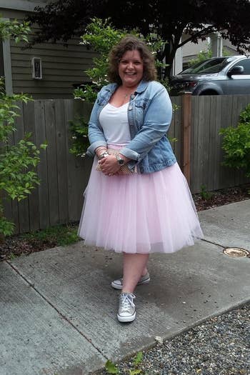 reviewer wearing the skirt in pink with sneakers and a denim jacket 