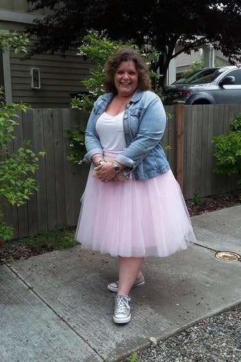 reviewer wearing the skirt in pink with sneakers and a denim jacket 