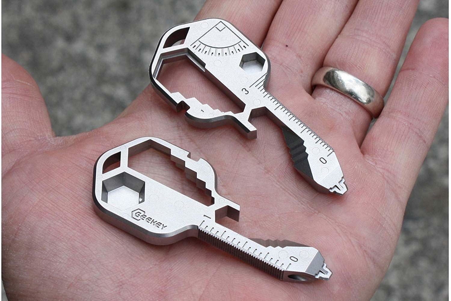 A person holds two key-shaped multi tools on their open palm