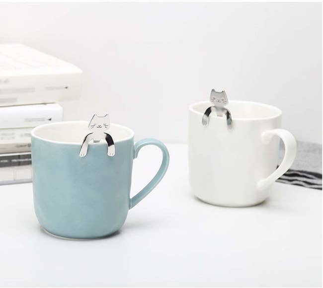 Silver cat spoons hanging over the edge of a cup 