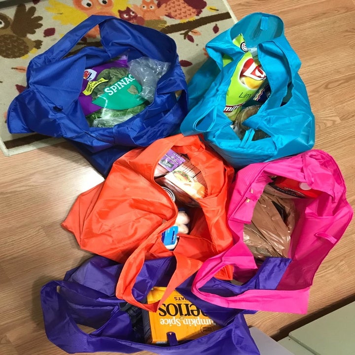 reviewer showing several reusable grocery bags with their groceries in them 