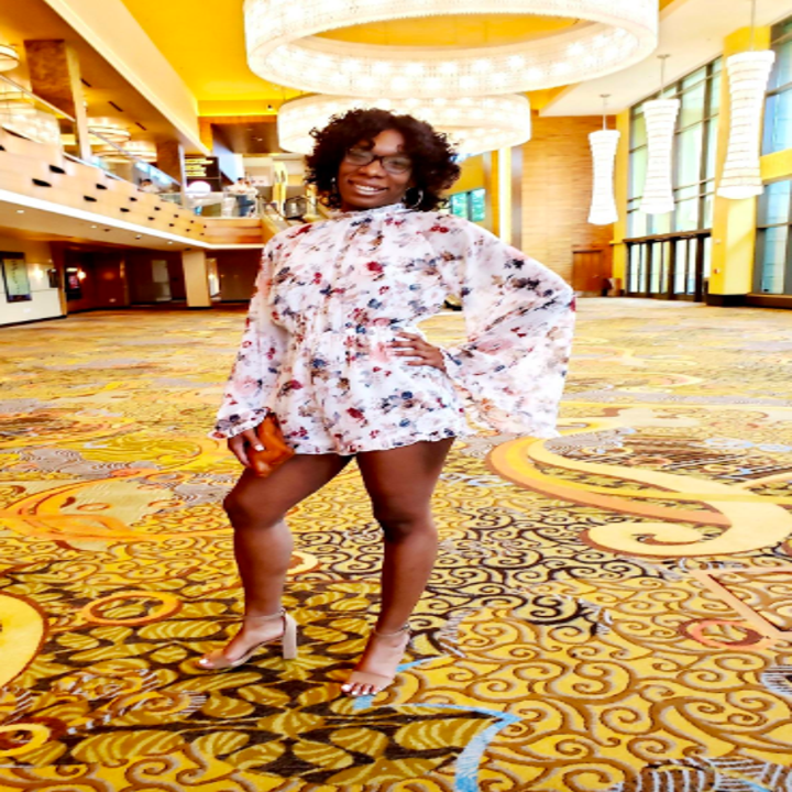 A reviewer wearing the high neck, long sleeve romper in white floral