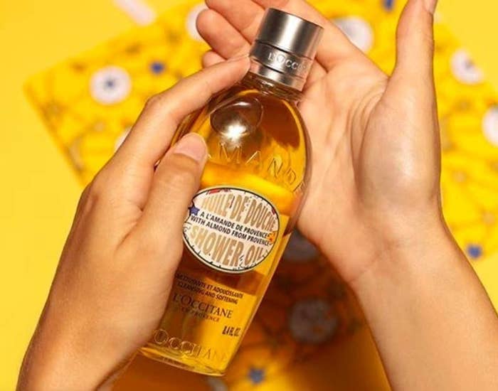 a person holding the bottle of shower oil