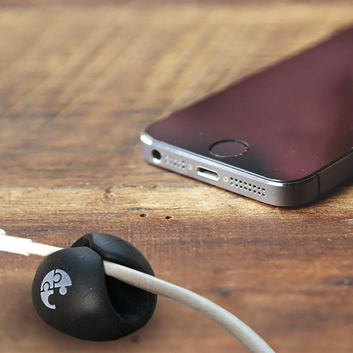 Black cable clip organizer holds a white charger next to a cell phone