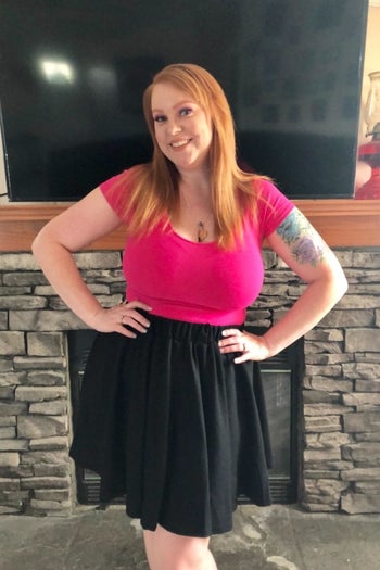 reviewer wearing the black skirt with a pink top 