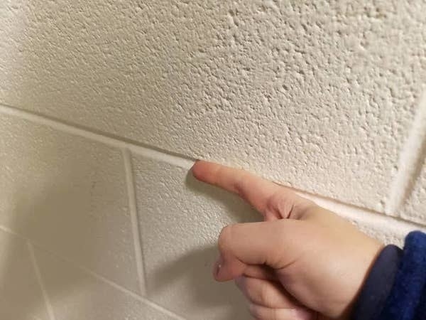 Picture of a person running their finger along a wall