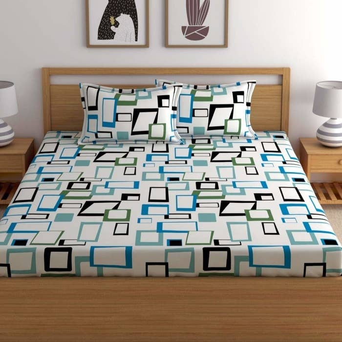 A white bedsheet with blue, teal, green and black squares printed on it