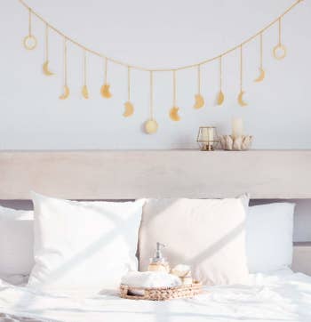 The moon cycle garland is hanging on the all over a bed headboard.